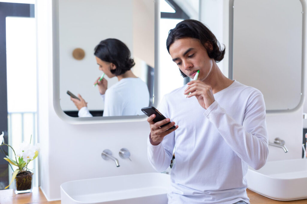 Man gebruikt een van de cadeau-ideeën voor mondgezondheid in de badkamer en poetst zijn tanden.